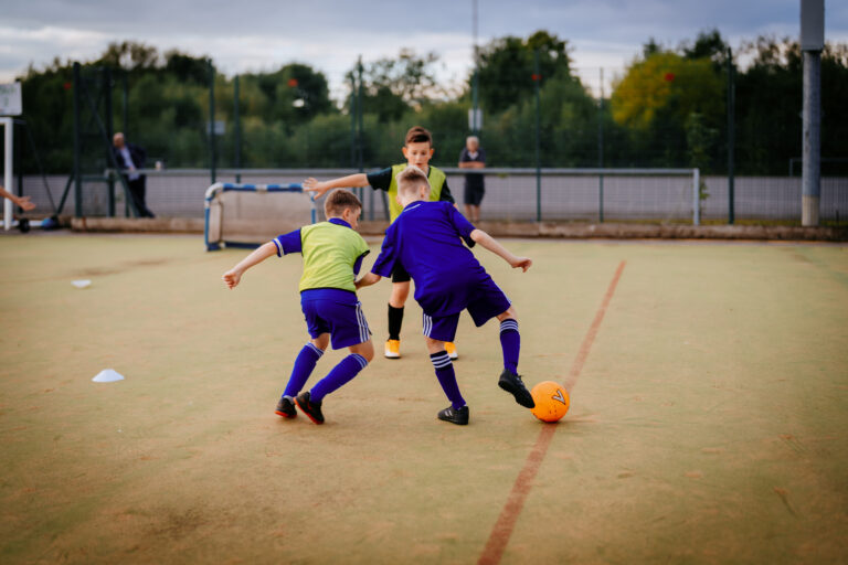 Three boys contesting the ball in a Foot-Tech training game