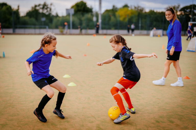 Two girls practising 1v1 skills with a female Foot-Tech coach