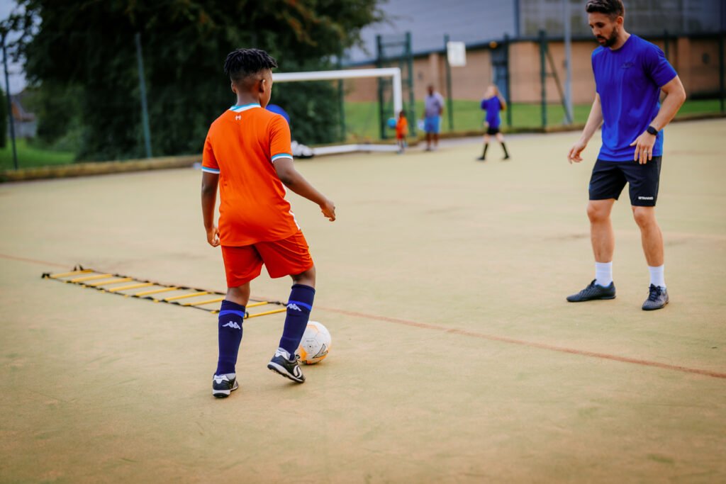 A Foot-Tech coach working one-to-one with a young player on ball control