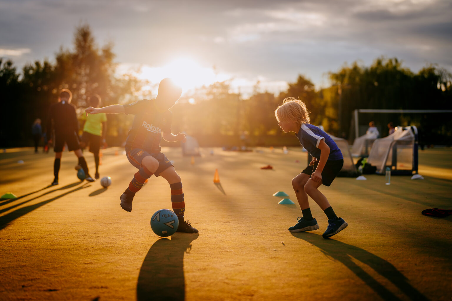 Two young players battling for the ball at golden hour during a Foot-Tech Academy session